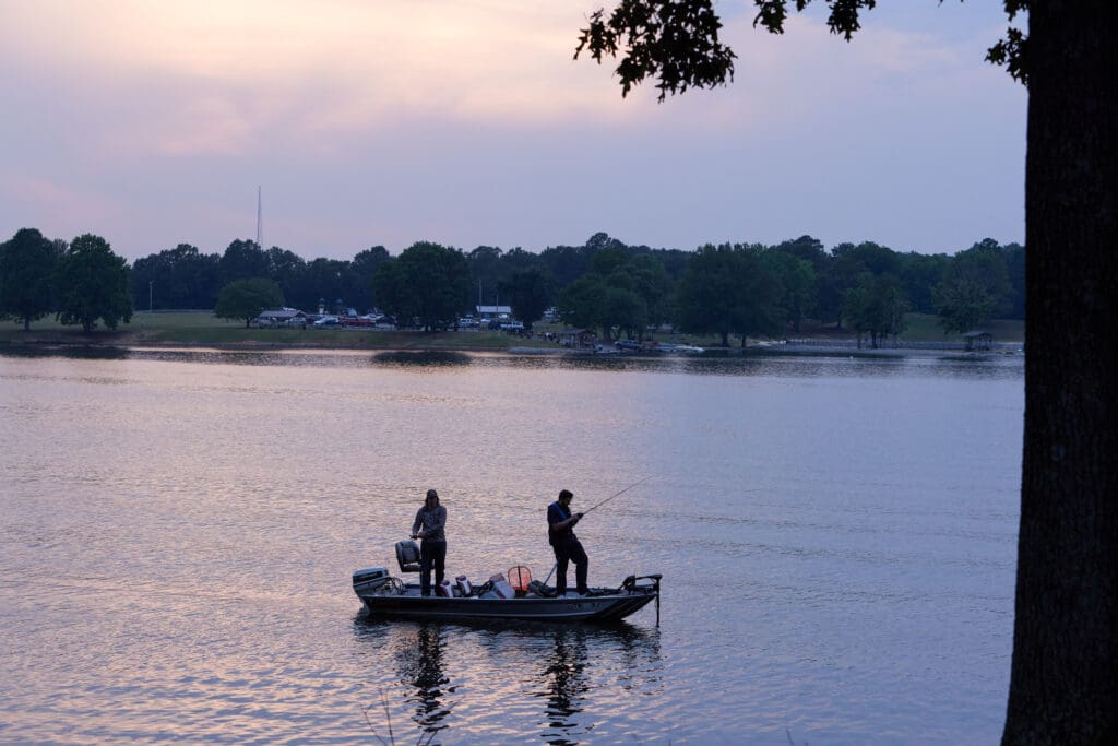 two men on a boat fishing on a large lake