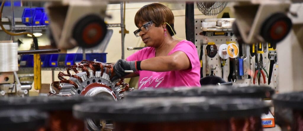african american women in a pink shirt works in a lab with safety goggles on